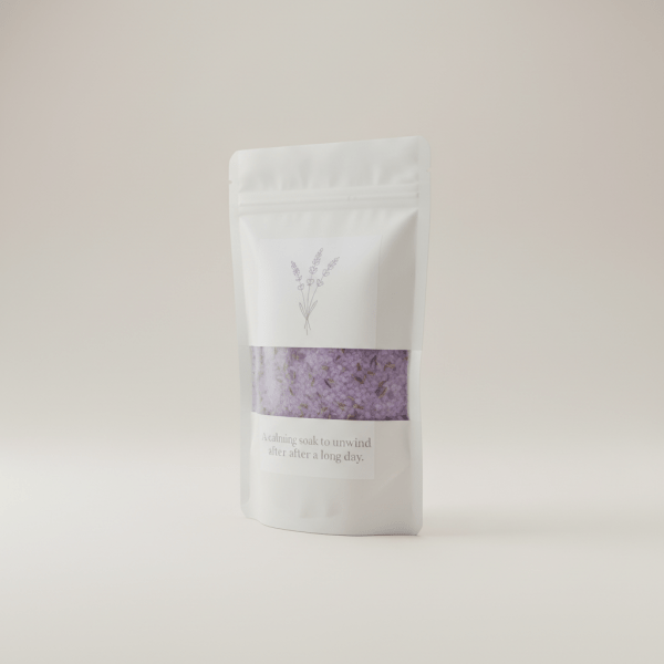 Professional e-commerce product photography of a **brandless** Lavender Bath Salts Premium Bag (A calming soak to unwind after a long day.). The entire environment is a perfectly uniform, flat, solid color #EAE9E7 (light warm gray) with absolutely no gradient, vignette, spotlighting, texture, noise, or grain. The object is centered and tiny, occupying only 25% of the frame, surrounded by massive negative space. The background and floor are a seamless, infinite cyclorama of solid color #EAE9E7 with no horizon line, no corner, and no visible wall/floor transition. Lighting: ultra-even high-key with very strong global illumination and soft, multi-directional bounced fill (studio light tent look). Bright exposure (lifted midtones and shadows, low contrast), slightly overexposed overall while preserving product detail. Fully diffuse, no hard shadows, no cast shadows; at most a barely visible neutral contact shadow. No harsh specular highlights. Framing: simple 3/4 view. Perfectly centered. Style: ultra-clean, minimalistic. No logos, no text, no distractions. 8k resolution, sharp details on the object.